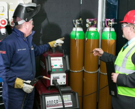 Gas safety consultant reviewing compressed gas cylinder storage on a client site